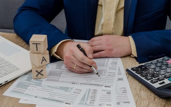Person calculating the impact of taxes on investment income using financial documents and a calculator